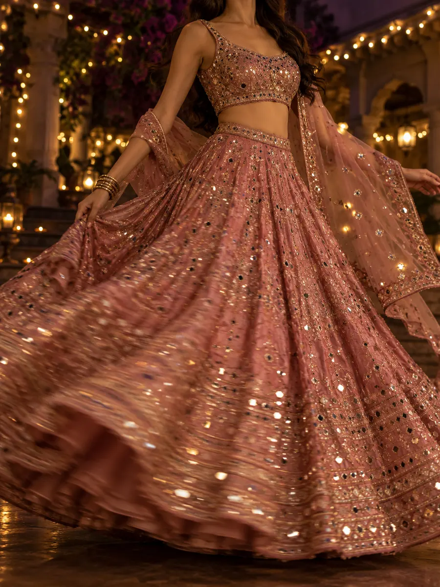 A woman twirling in a rose mirror-work lehenga under strings of fairy lights at a sangeet.